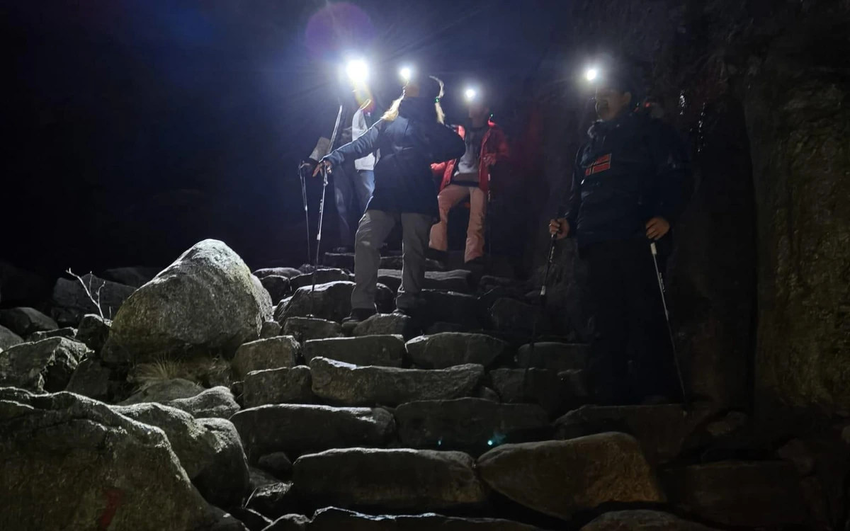 Hikers with headlamps climbing stone steps in the dark