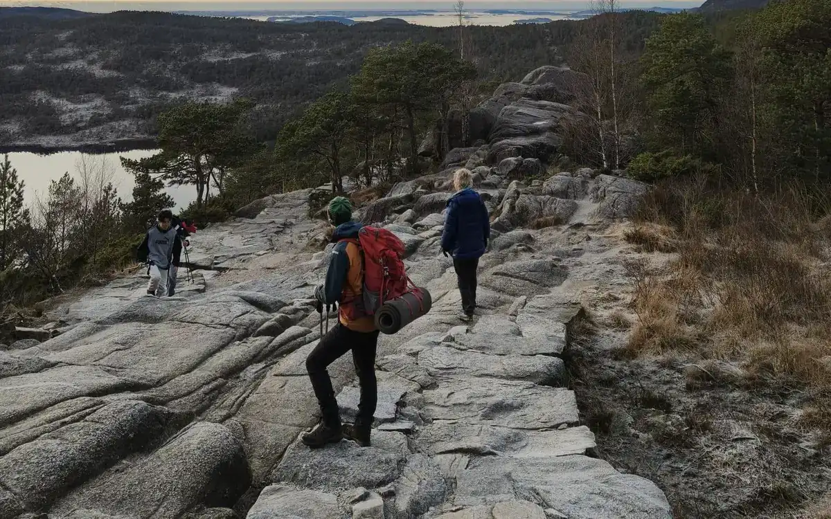 Hikers with backpacks crossing bare granite slabs on a mountain path