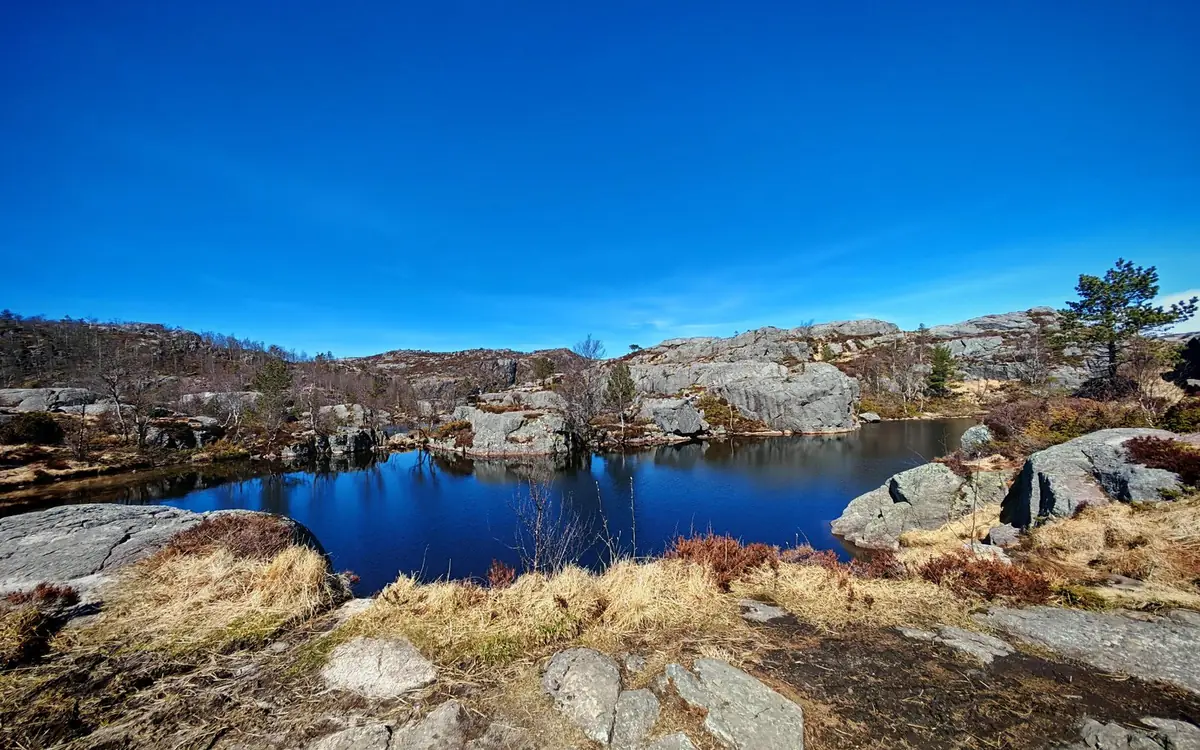 A blue mountain lake among granite slabs and dry grass